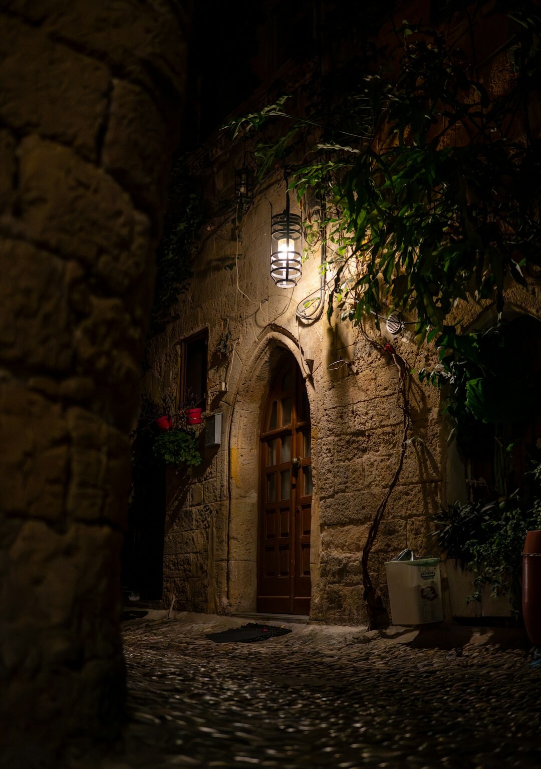 Foggy old European stone street at night with a single lit lamp